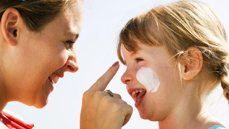 Mother applying CBD Sunscreen to her daughter with smiling faces
